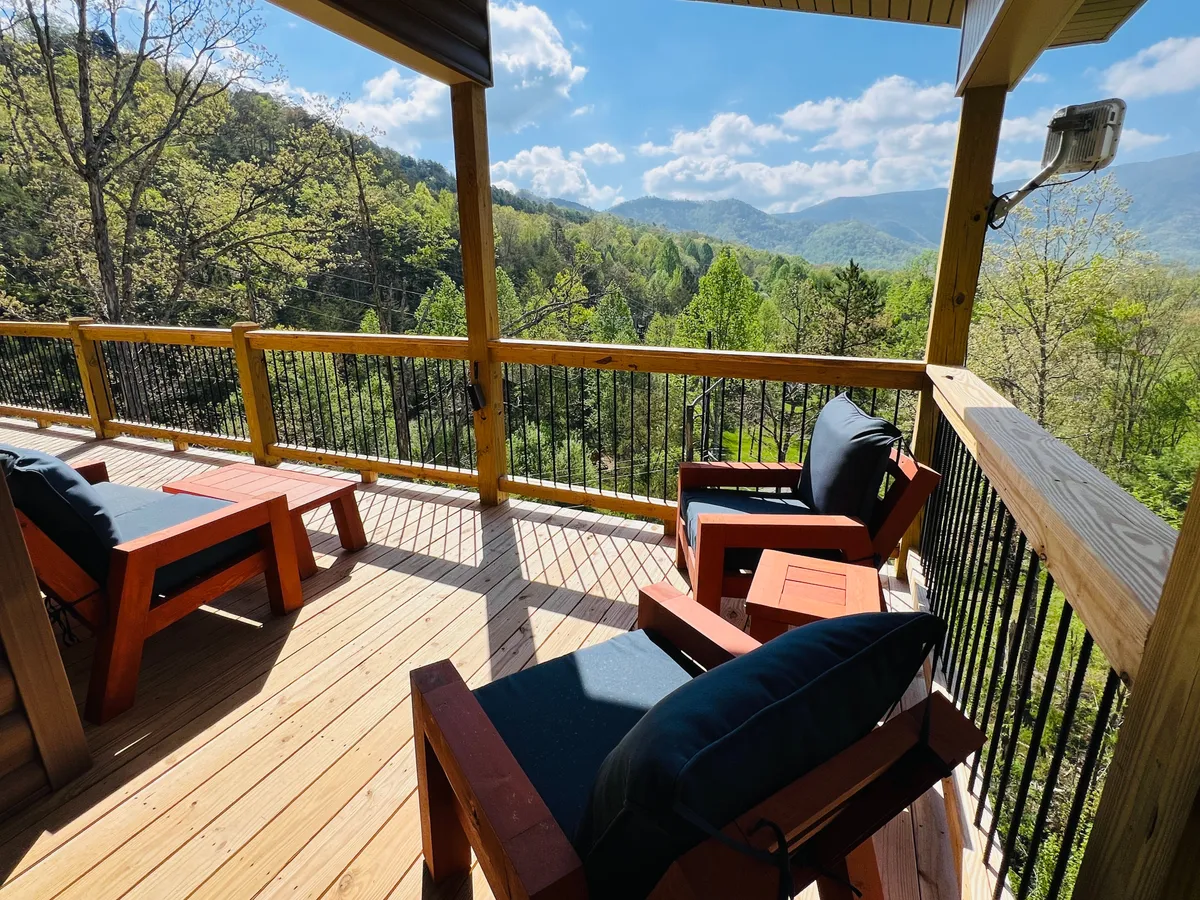 A scenic wooden deck with comfortable seating overlooks a breathtaking mountain view. The tranquil scene suggests a perfect setting for relaxing, enjoying a sunset, or watching wildlife. The colors of the sky hint at evening, enhancing the sense of intimacy and seclusion.