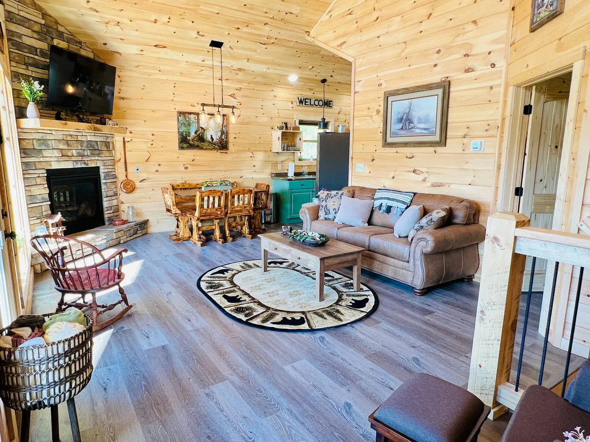 A welcoming living room with a plush sofa (which doubles as a sleeper sofa), a stone fireplace, a wooden dining table, and a stylish rug. The room exudes warmth and togetherness, perfect for relaxing in the evening or accommodating additional guests.