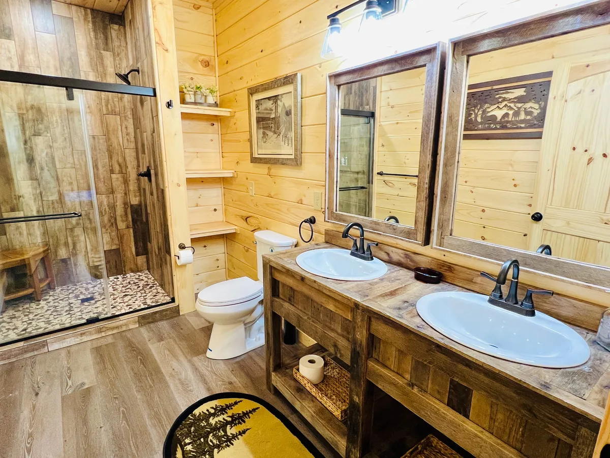 A spacious bathroom with a double vanity, large glass shower, wooden shelving, and a decorative mirror. The bathroom feels serene and luxurious, providing an ideal space for rejuvenation after a day of mountain adventures.