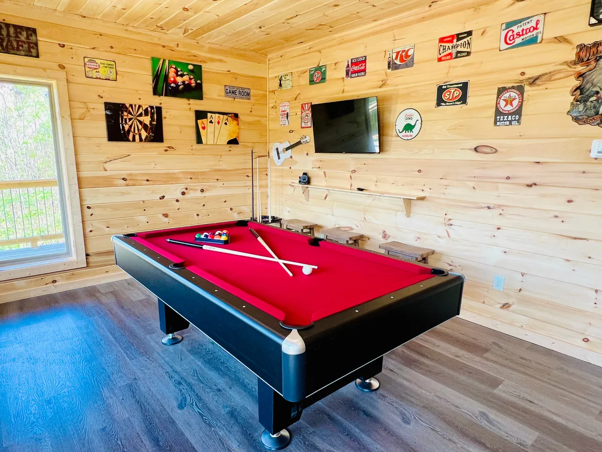 A lively game room featuring a pool table, dartboard, wall decor, and a television, all suggesting a playful space for socializing and entertainment.
